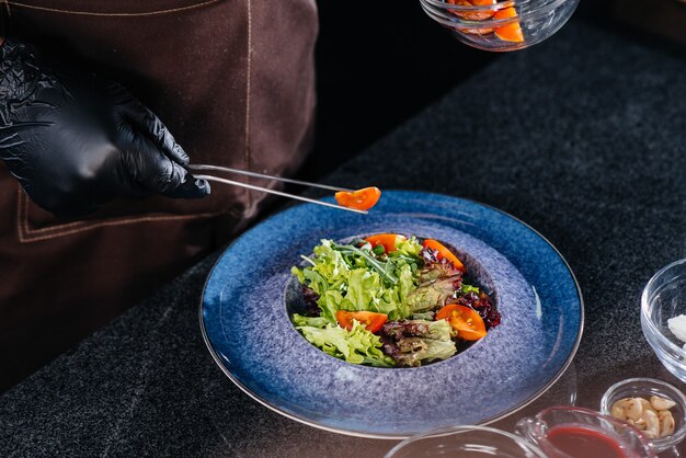 Ein professioneller Koch bereitet in einem modernen und stilvollen Restaurant einen köstlichen frischen Salat aus grünem Gemüse und saftigem Kalb zu