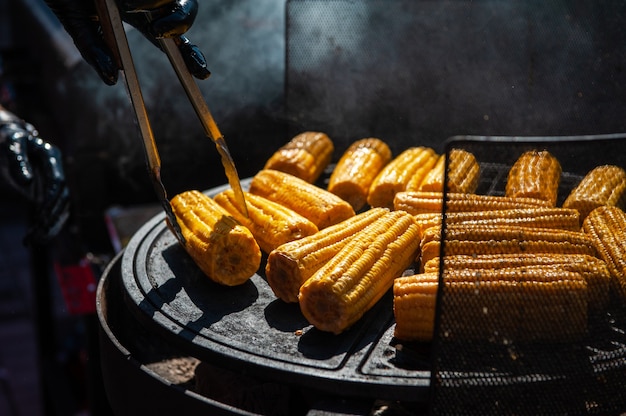 Ein professioneller Koch bereitet Mais auf dem Grill im Freien, Essen oder Catering-Konzept zu