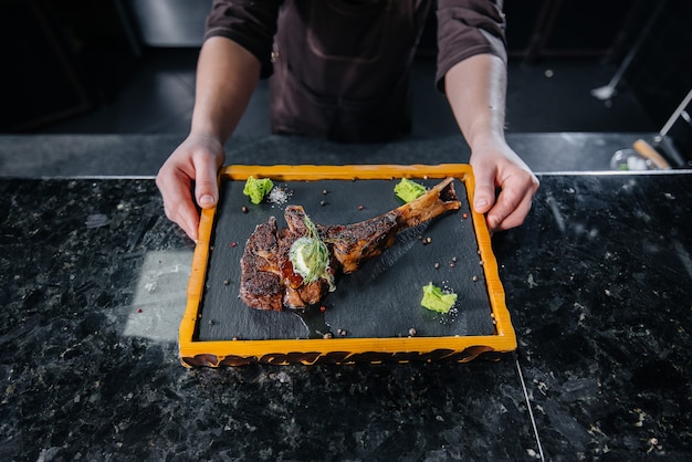 Ein professioneller Koch serviert wunderbar ein saftiges Grillsteak mit Butter und Gewürzen beautifully