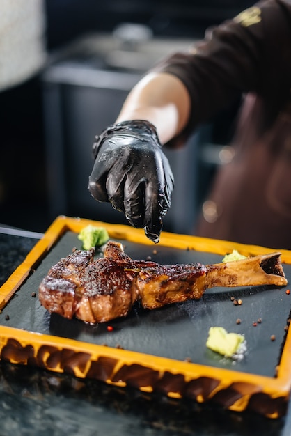 Ein professioneller Koch serviert wunderbar ein saftiges Grillsteak mit Butter und Gewürzen