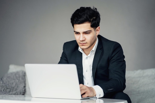 Ein professioneller männlicher Anwalt arbeitet an einem Laptop, der auf der Couch eines Managers sitzt