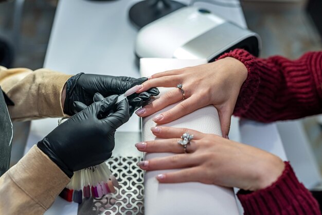 Ein professioneller Nagelverlängerungsmeister wählt während einer Epidemie eine Farbe für seinen Kunden aus