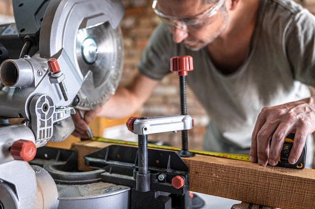 Ein professioneller Tischler arbeitet mit einer Kreissäge Gehrungssäge in einer Werkstatt.