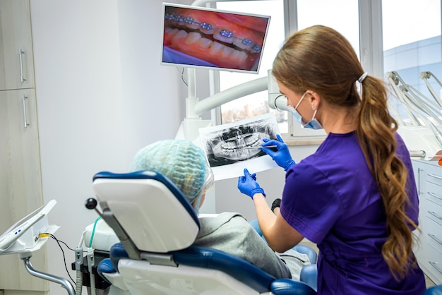 Ein professioneller Zahnarzt zeigt den Patienten Bilder seines Kiefers und seiner Zähne Das Konzept der Bilder des Kiefers und der Zähne beim Zahnarzt