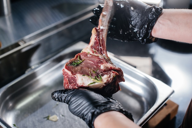 Ein Profikoch mariniert und bereitet aus einem frischen Stück Fleisch ein saftiges Steak zu