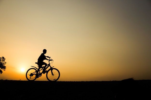 Ein Radfahren-Trainings-Wellnesskonzept des Jungeneignungsschattenbild-Sonnenaufganges.