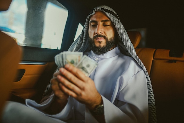 Ein reicher Mann Ein arabischer Mann in traditioneller Kleidung in einem Auto, das Geld hält