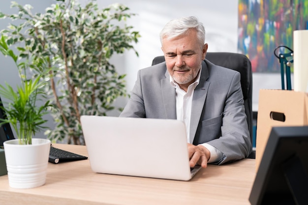 Ein reifer Mann mit grauem Haar und Dreitagebart schickt eine E-Mail an seine Kollegen und unterzeichnet Berichte