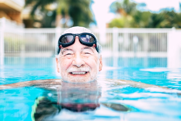 Ein reifer Mann oder Senior am Pool, der lächelnd in die Kamera schaut und allein Spaß hat - gesunder und Fitness-Lifestyle