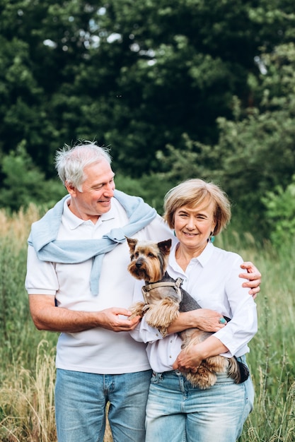 Ein reifes Paar geht mit einem Hund in einem Park spazieren