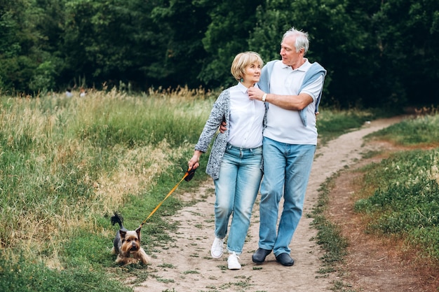 Ein reifes Paar geht mit einem Hund in einem Park spazieren