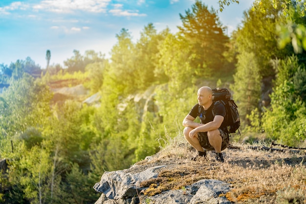 Ein Reisender betrachtet die Landschaft um sich herum auf der Spitze der Klippe im Sommer bei warmem Wetter.