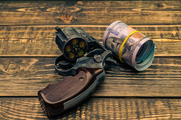 Ein Revolver mit Dollar auf einem Holztisch.