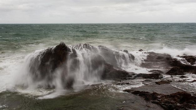 Ein riesiger Meeresfelsen, der von einer großen Welle bedeckt ist.