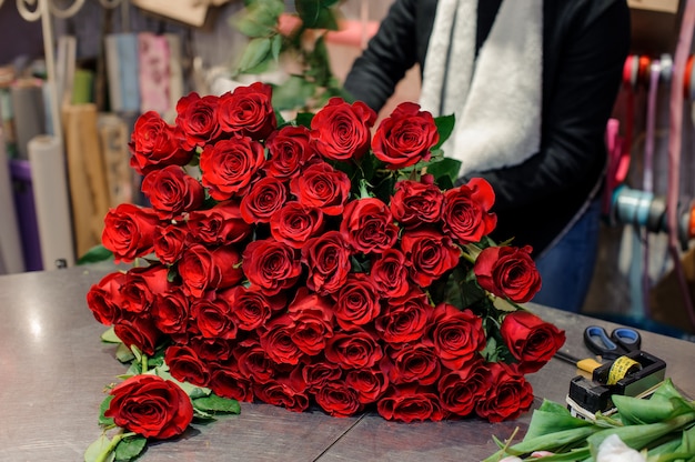 Ein riesiger Strauß roter Rosen liegt auf dem Tisch