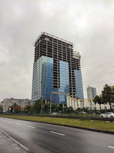 Ein riesiger unfertiger Wolkenkratzer mit Glaswänden auf dem Hintergrund einer Asphaltstraße