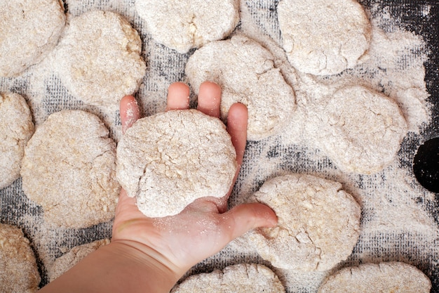 Ein rohes Hähnchenschnitzel in einer Kinderhand und viele Schnitzel in Paniermehl auf einem Plastikbrett