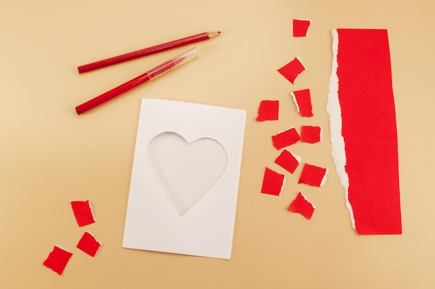 Ein Rohling für einen Valentinstag aus Papier in Form eines Herzens mit einem Bleistift und einem Filzstift