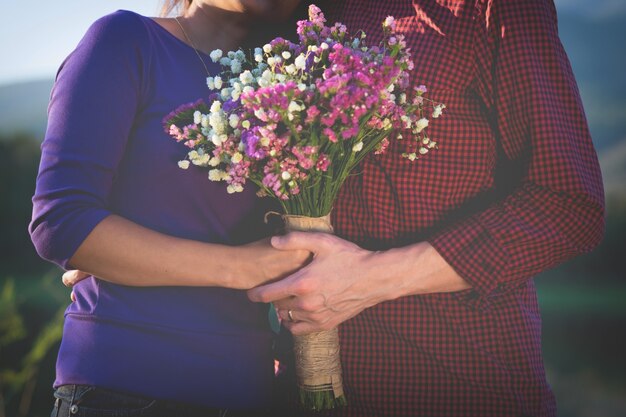 Ein romantisches Paar hält Valentines Geschenk und Blumen, Vintage Ton