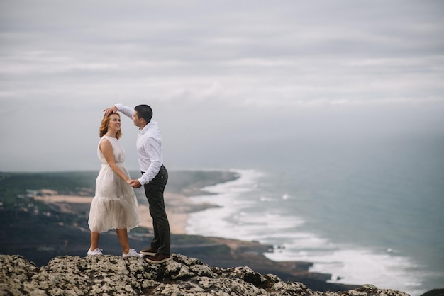 Ein romantisches Paar steht auf einer Klippe am Meer gegen den Himmel