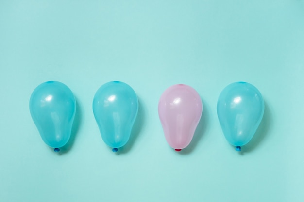 Ein rosa Ballon unter vielen blauen Luftballons auf blauem Hintergrund. Konzept der Gleichstellung der Geschlechter