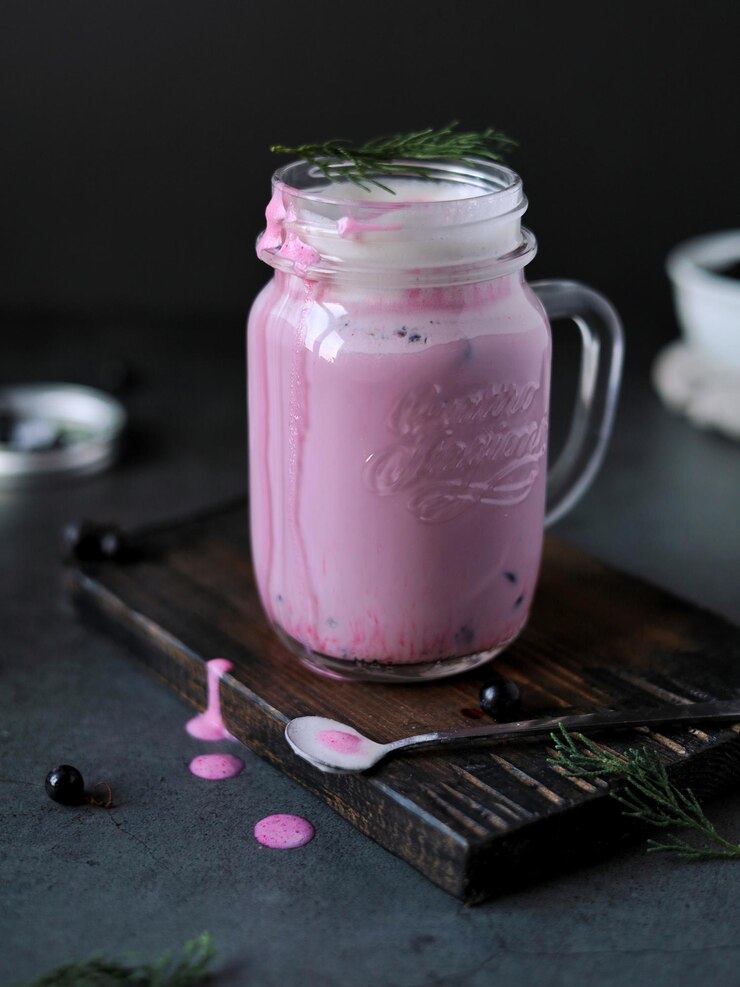Ein rosa Getränk gesunder Smoothie aus Beeren und Milch in einem dekorativen Glas auf dem Tisch