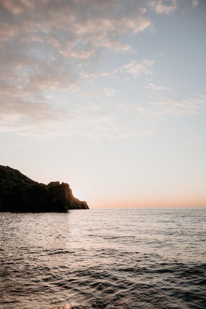 Ein roter brennender Sonnenuntergang über dem Meer mit felsiger vulkanischer Klippe abstrakter Natursommer oder Frühlingsozean