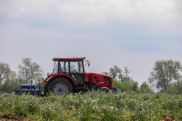 Foto ein roter traktor fährt über das feld, um die landwirtschaft zu pflügen