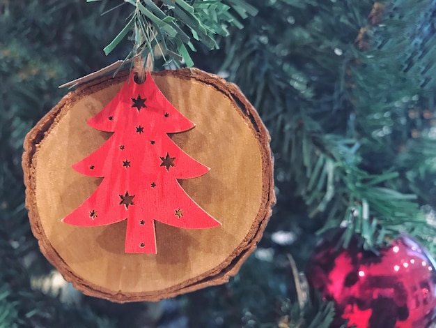 Ein roter Weihnachtsformbaum auf dem hölzernen Bauholz, das während an glücklicher Jahreszeit verziert.