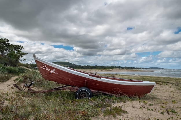 Ein rotes Boot am Strand mit dem Wort „Sunshine“ an der Seite