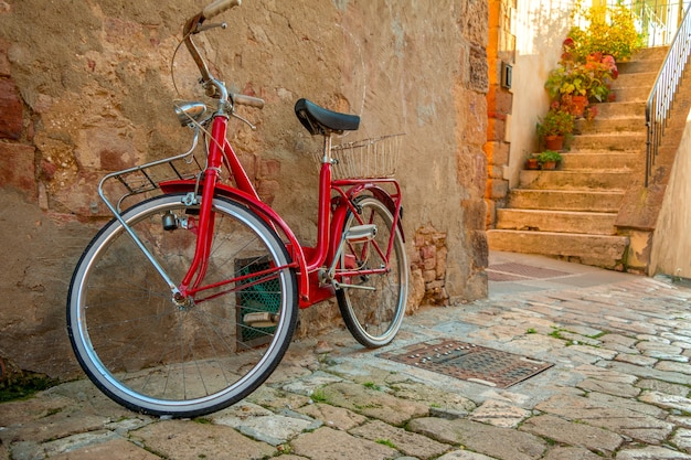 Ein rotes Fahrrad steht in der engen Straße der Altstadt in der Nähe der Steinmauer des Gebäudes