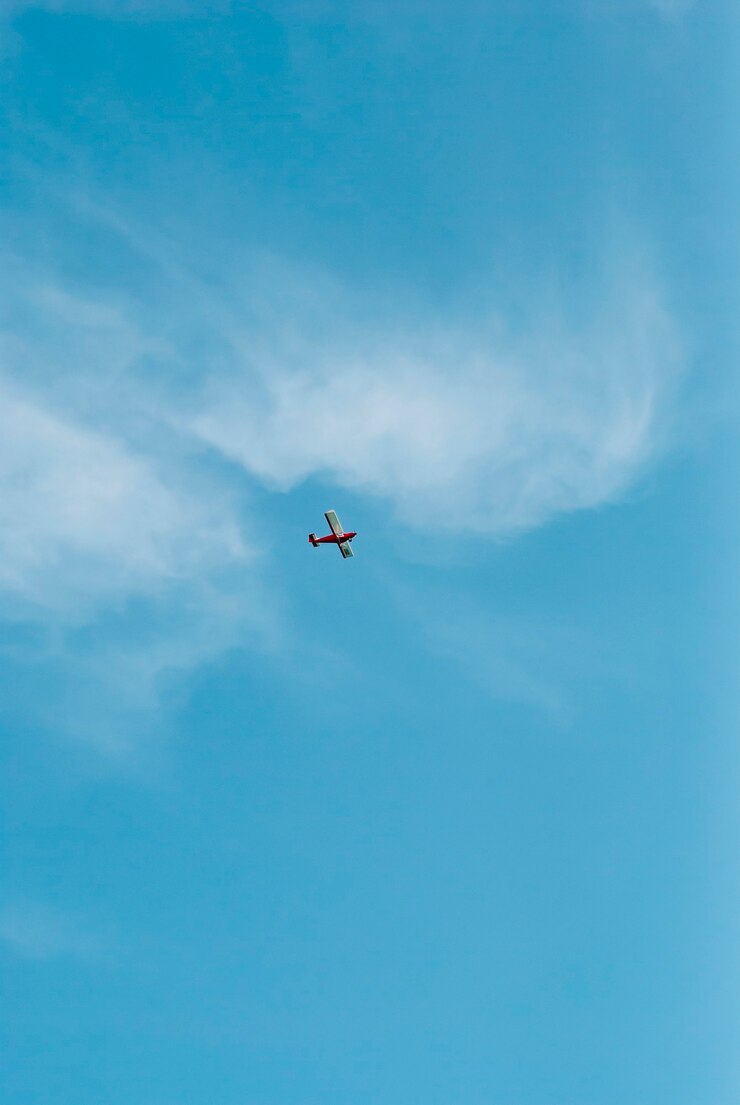 Ein rotes Flugzeug zwischen weißen Wolken am blauen Himmel