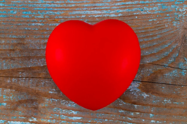 Ein rotes Herz auf dem hölzernen Hintergrund.