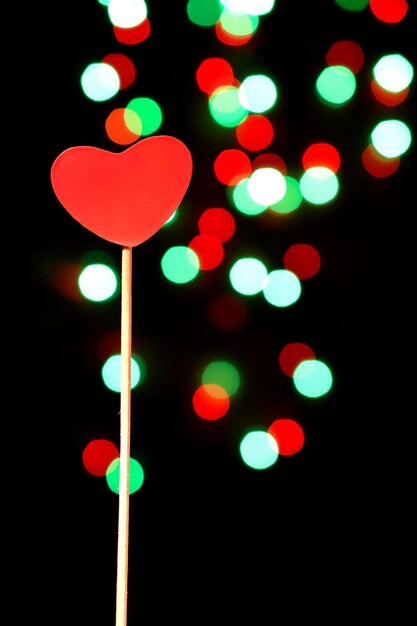 Ein rotes Herz auf einem Stock vor einer Reihe von Lichtern
