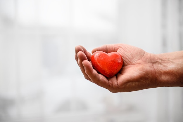 Ein rotes Herz in der Hand eines Mannes Das Konzept der Gesundheitsspende Liebe und Nächstenliebe