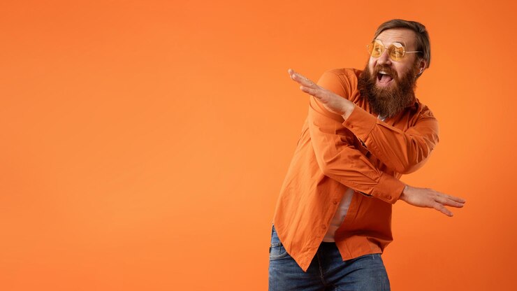 Foto ein rothaariger, bärtiger typ mit sonnenbrille tanzt mit lustigen bewegungen im studio