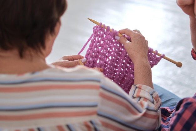 Ein ruhiger Nachmittag zu Hause, wo eine Mutter ihrem erwachsenen Sohn, der sie besucht, die Kunst des Stricken lehrt.