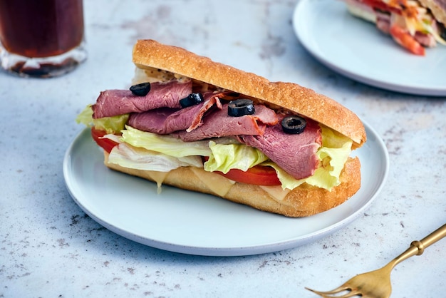 Ein Sandwich mit Fleisch und Oliven auf einem Teller