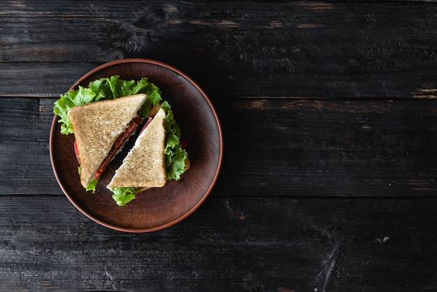 Ein Sandwich mit Speck, Salat und gegrillter Tomate mit Hühnchen und Avocado. Platz für Text