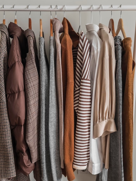 Ein Satz Damen-Herbstkleidung auf einem Kleiderbügel. Pullover, Hemden, Mäntel, Daunenjacken, Hosen, Jeans, gemütliche, bequeme Freizeitkleidung