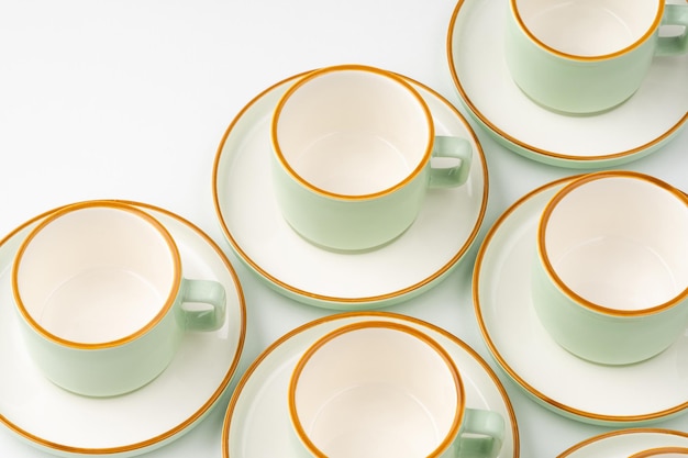 Ein Satz Teetassen aus weißer und pastellgrüner Keramik mit orangefarbenen Umrissen