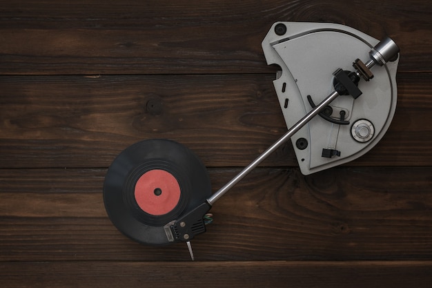 Ein Schallplattenspieler und eine rote Scheibe auf einem Holztisch. Retro-Technik zum Abspielen von Musik.