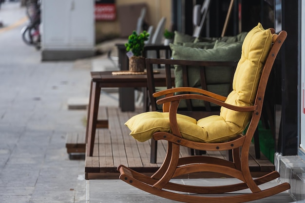 Ein Schaukelstuhl aus Holz mit einem weichen gelben Sitz in einem Schaufenster, weicher Fokus