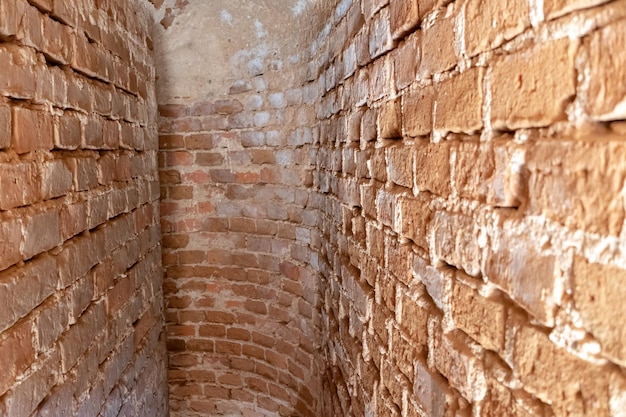 Ein schmaler Korridor oder Durchgang in einem alten Gebäude oder Schloss Alte rote Backsteinmauern Wendeltreppe im Glockenturm der alten Kirche Historischer Wert und Erbe