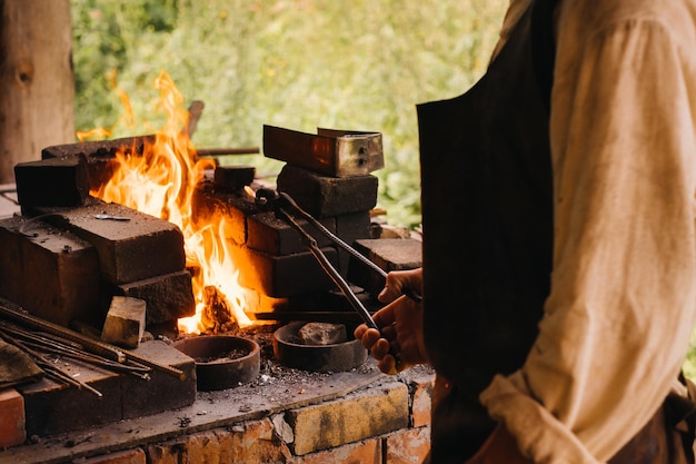 Ein Schmied härtet Stahl bei hoher Temperatur in einem selbstgebauten Ofen im Dorf