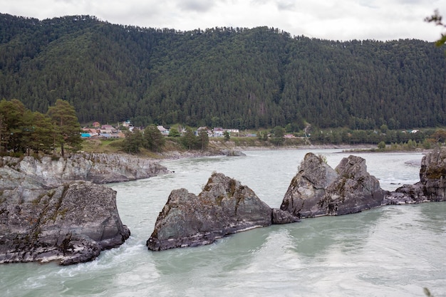 Ein schnell fließender breiter und voll fließender Big Mountain River. Große Felsen ragen aus dem Wasser.