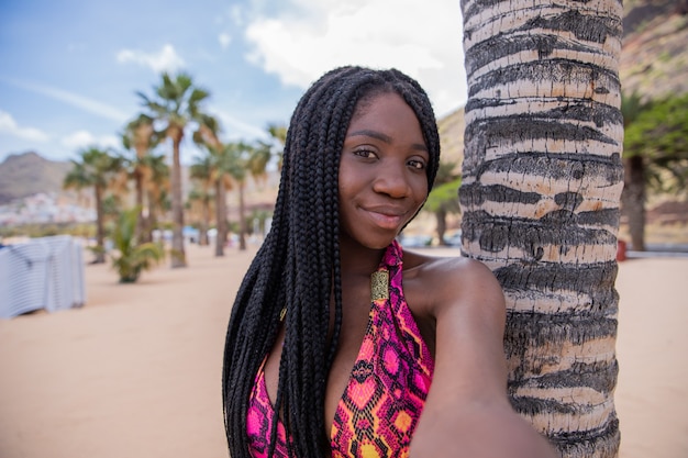 Ein schönes afrikanisches Mädchen im Urlaub macht ein Selfie an einem tropischen Strand