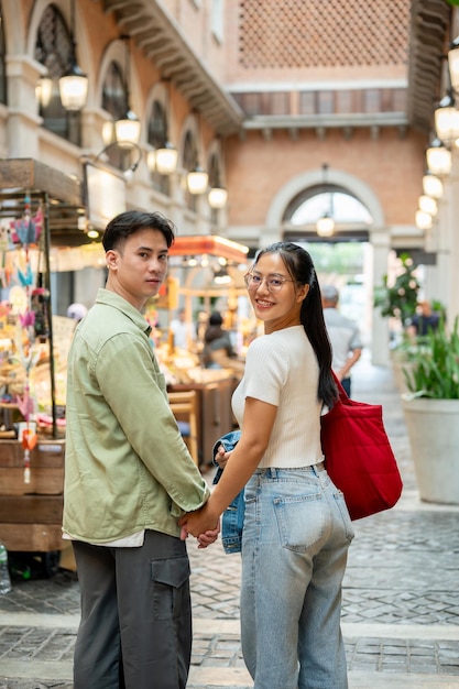 Ein schönes asiatisches Paar hält sich an den Händen, während es auf einem Date durch einen schönen Markt geht