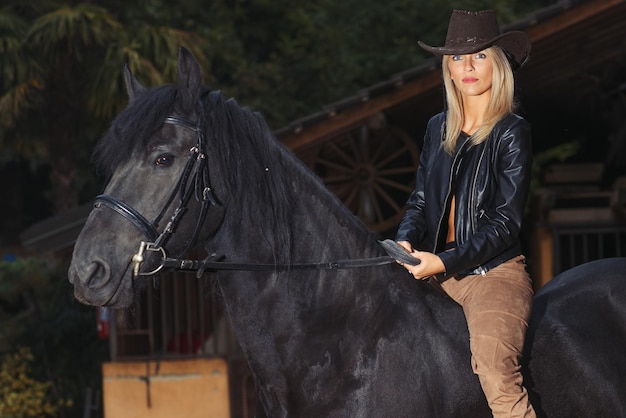 Ein schönes blondes Mädchen über einem schwarzen Pferd