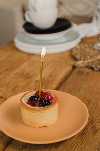 Ein schönes Dessert mit Kerze und Beeren steht auf dem Küchentisch Geburtstagskonzept